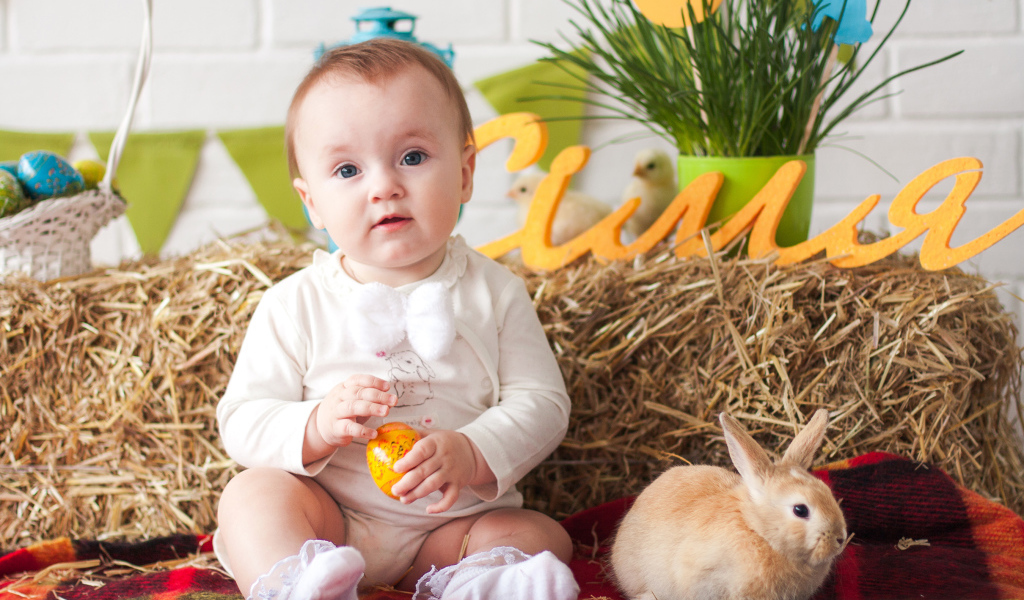 Маленький ребенок с крашеным яйцом и декоративным кроликом