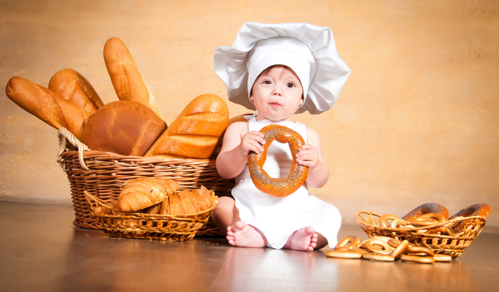 Маленький поваренок на столе со свежей выпечкой