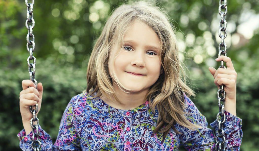 Маленькая милая голубоглазая девочка на качели