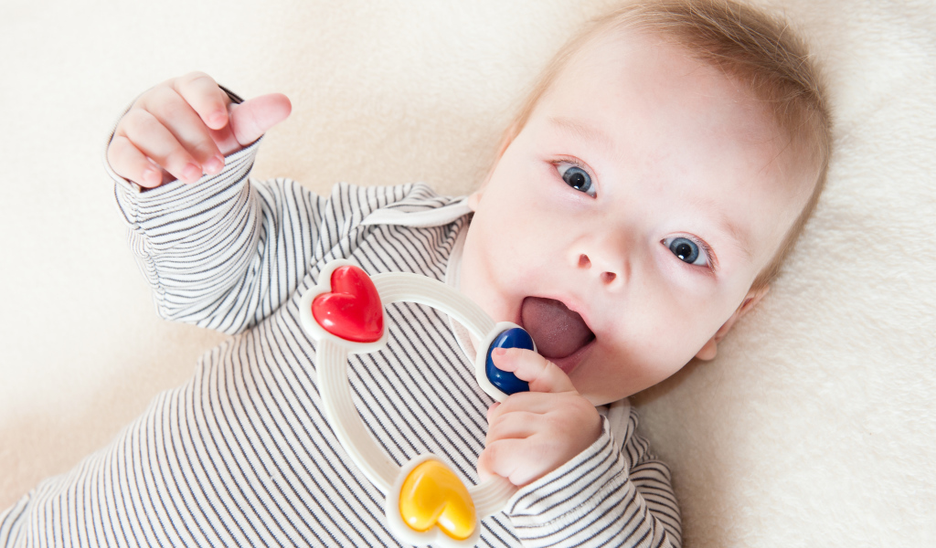 Маленький забавный голубоглазый ребенок с погремушкой