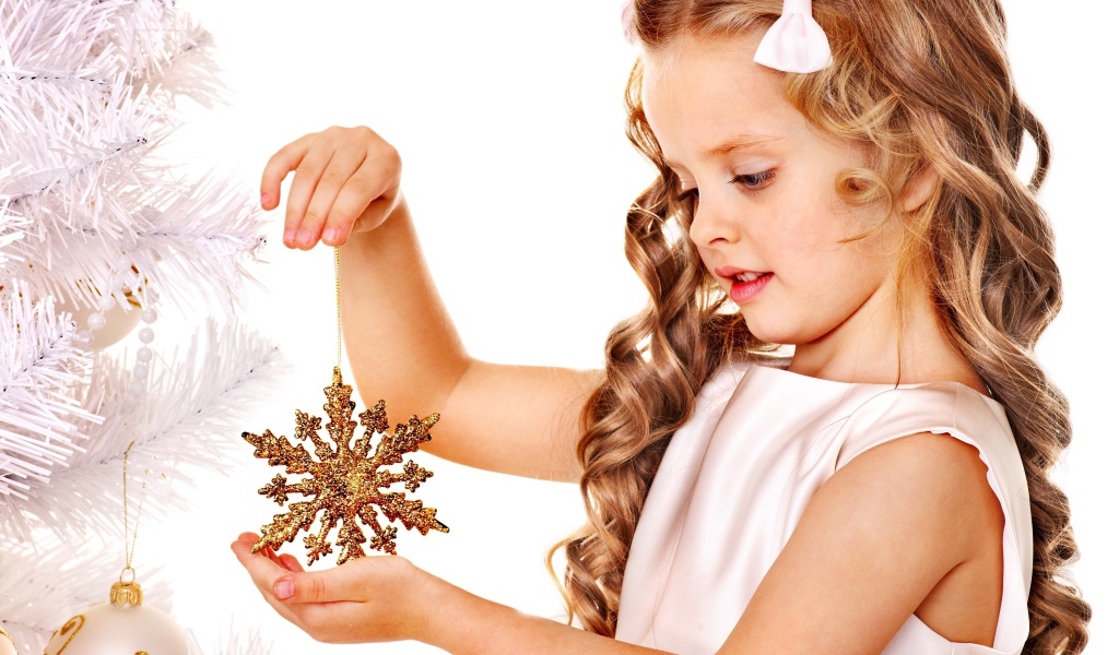 Маленькая девочка держит елочную игрушку снежинку в руке