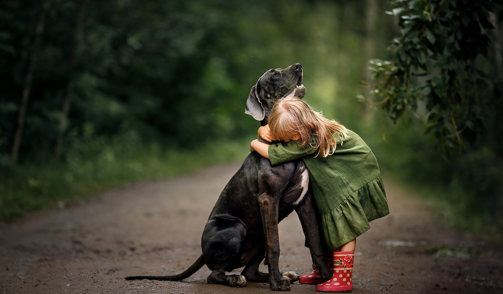 Маленькая девочка обнимает большого черного дога
