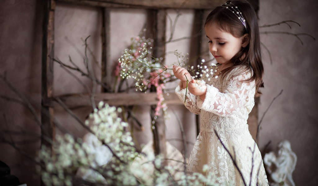 Маленькая девочка в красивом платье с белыми цветами в руке