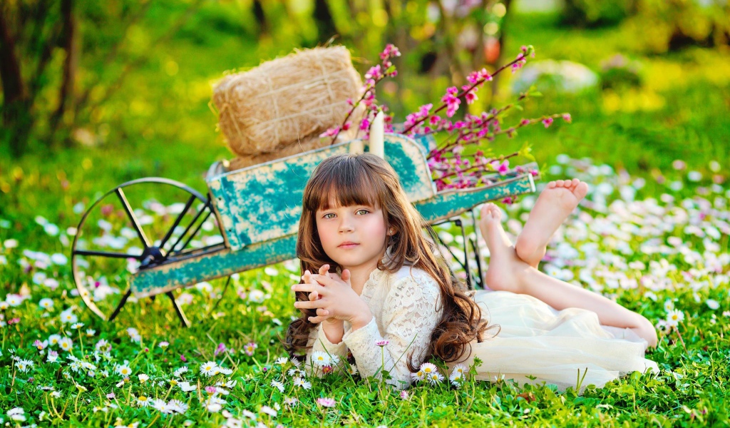 Маленькая девочка лежит на зеленой траве 