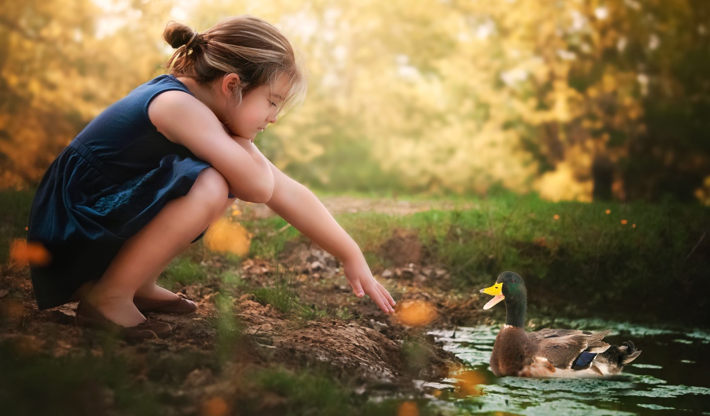 Маленькая девочка играет с уточкой в воде