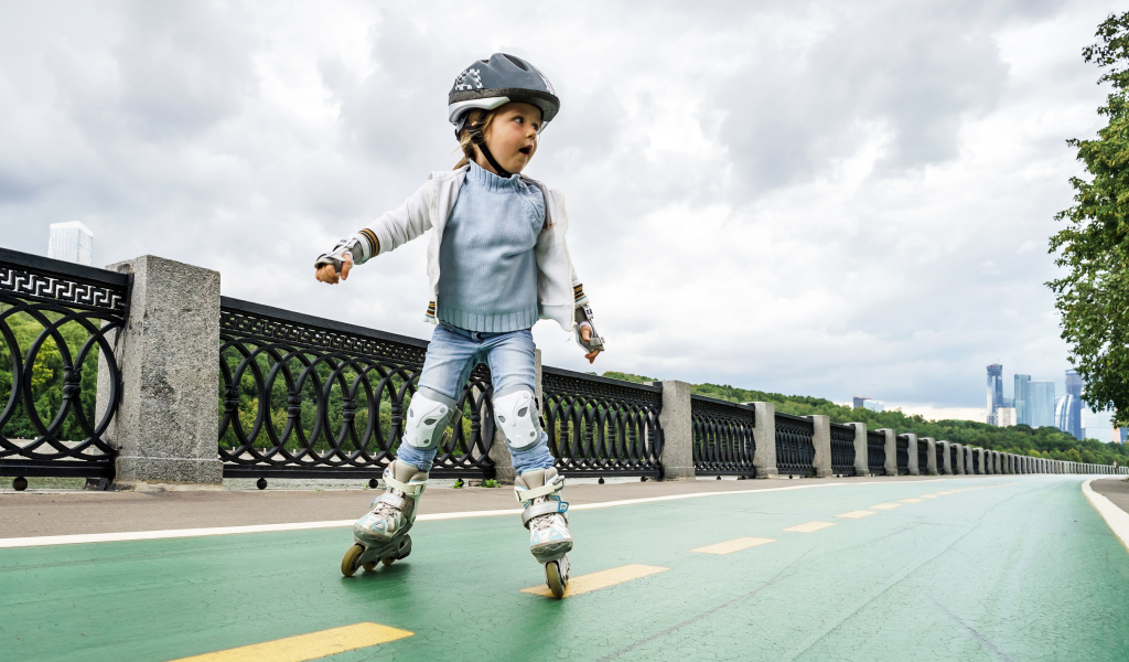 Маленькая девочка катается по мосту на роликах