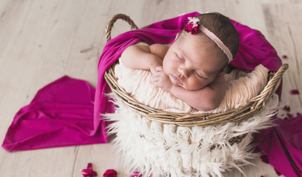 Маленькая девочка спит в корзине под покрывалом