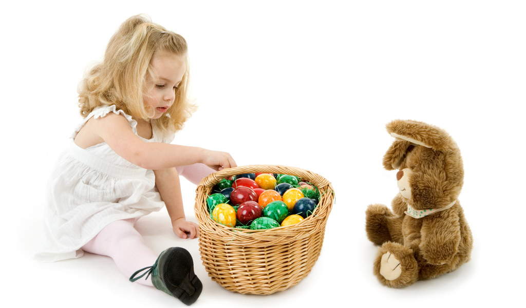 Маленькая девочка с корзиной крашеных яиц и игрушечным кроликом