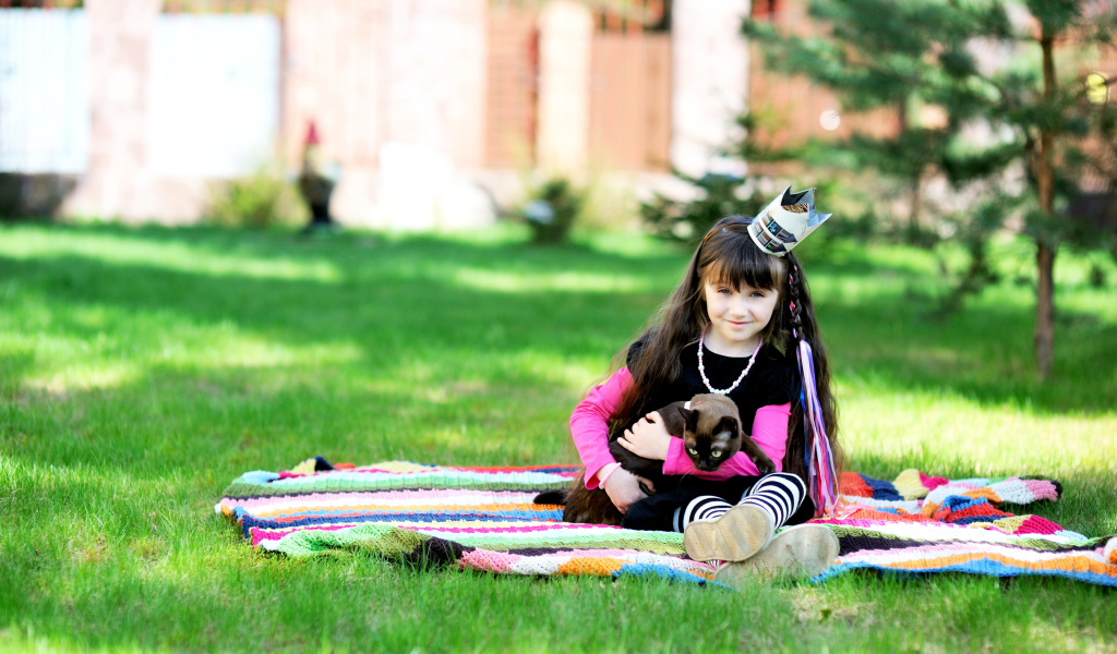 Маленькая девочка с котом сидит на зеленой траве