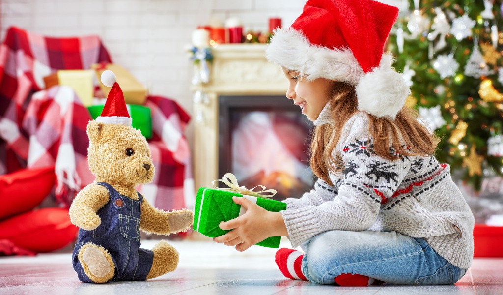 Маленькая девочка с медвежонком Тедди у елки с подарками на Новый год