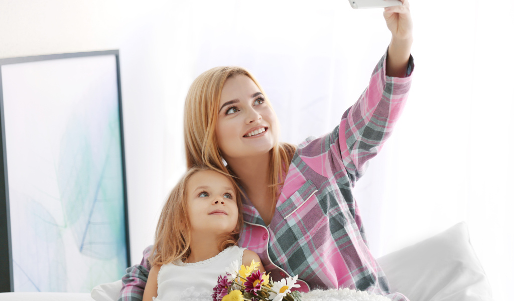 Маленькая девочка с мамой делают фото на смартфон