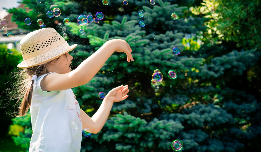 Маленькая девочка с мыльными пузырями у елки