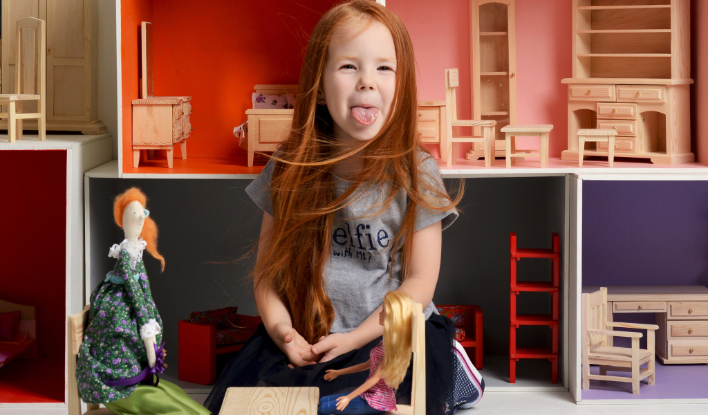 Маленькая длинноволосая девочка показывает язык