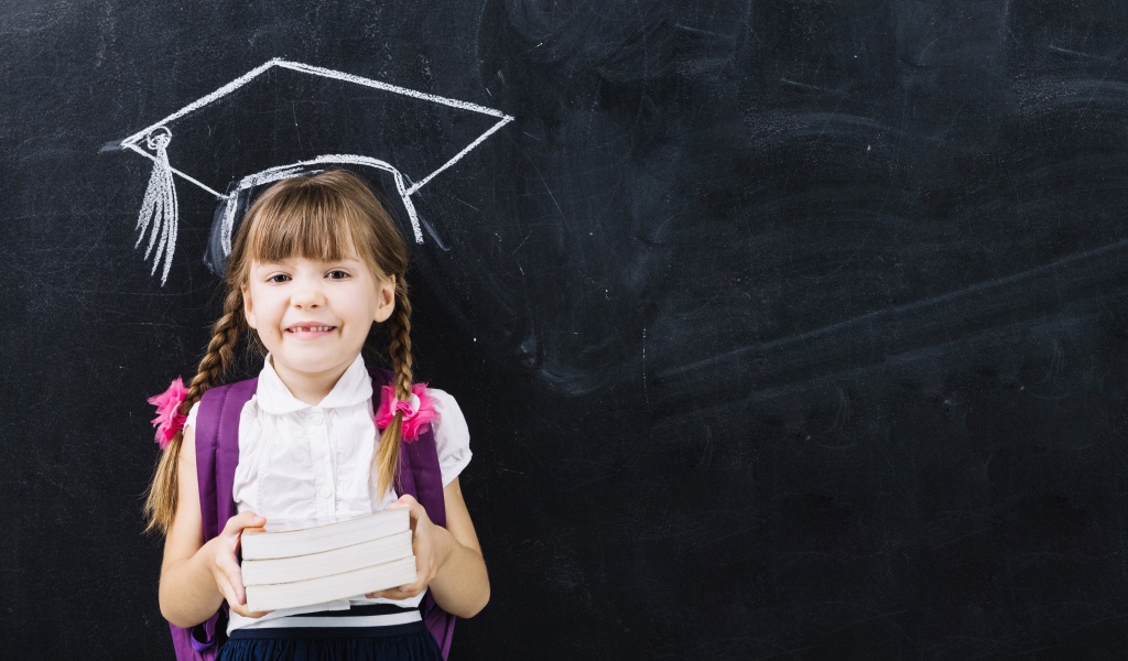 Маленькая школьница с книгами у доски 