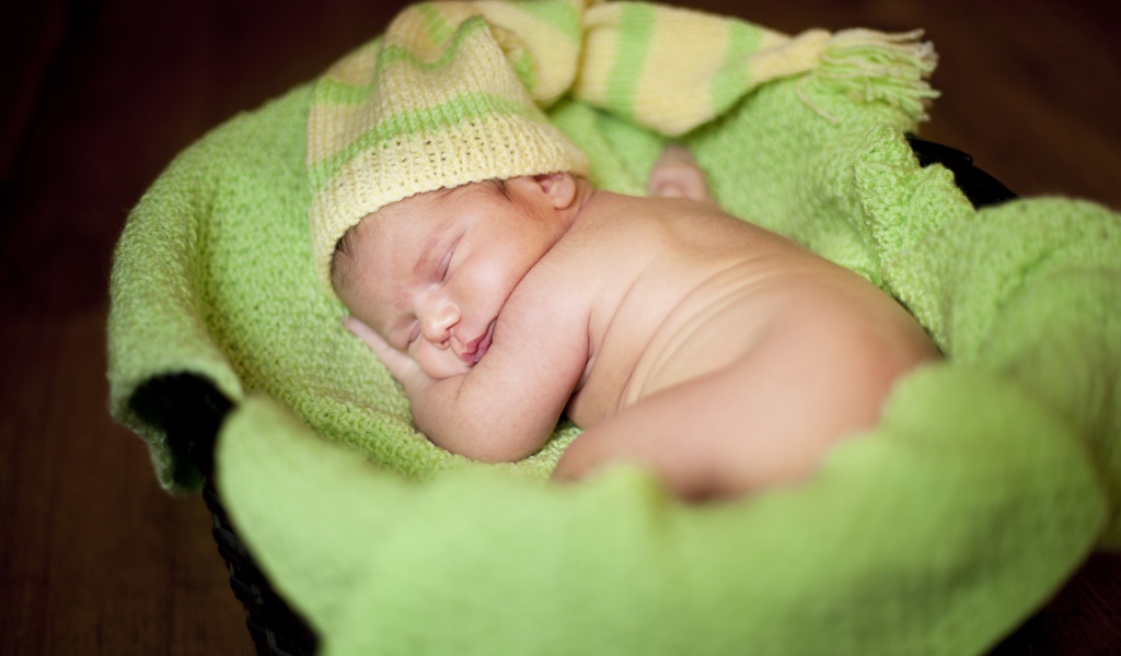 Маленький спящий грудной ребенок на зеленом покрывале 