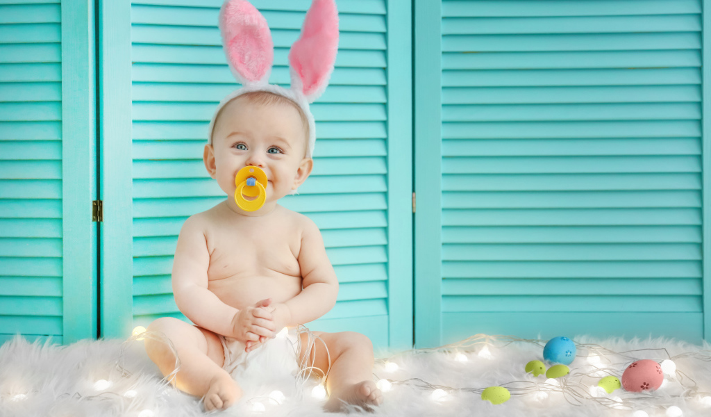 Маленький улыбающийся малыш с ушками зайчика на голове