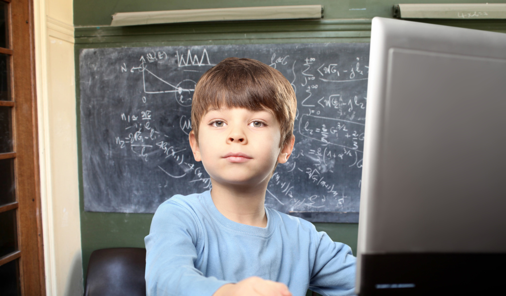 Мальчик школьник делает уроки за ноутбуком