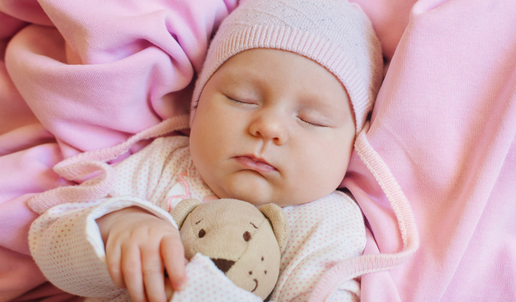 Спящий ребенок обнимает любимую игрушку