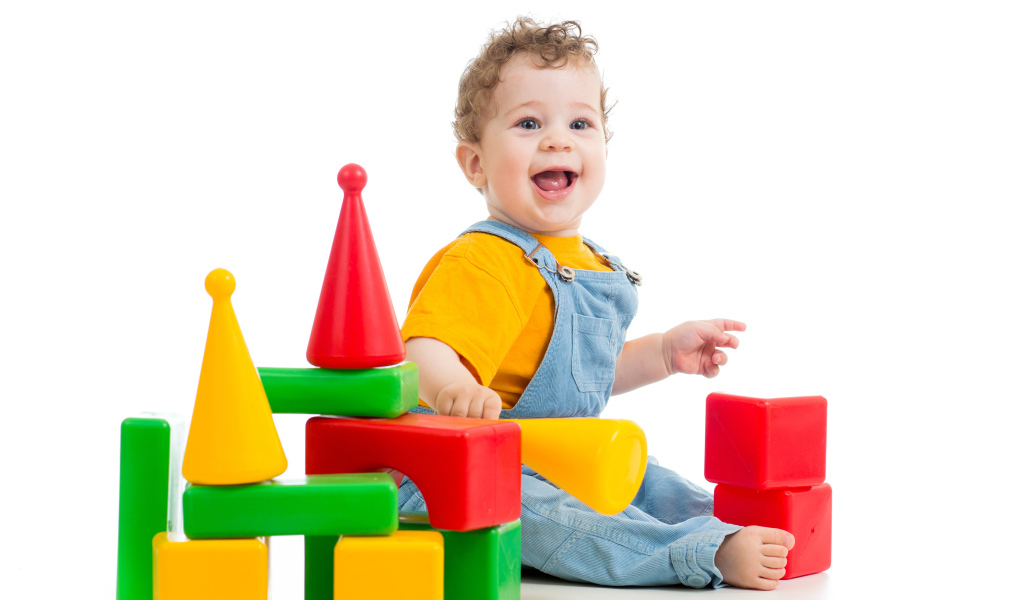 Улыбающийся милый малыш играет с кубиками на белом фоне