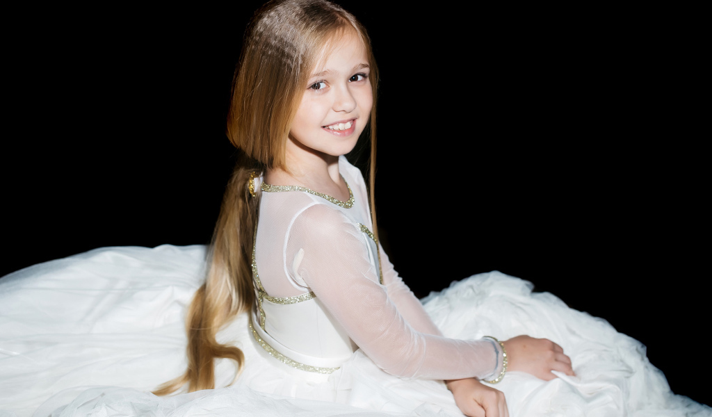 Улыбающаяся девочка в красивом белом платье на черном фоне