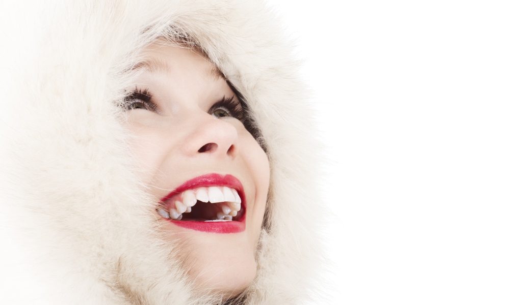 Улыбающаяся девушка в меховом капюшоне на белом фоне