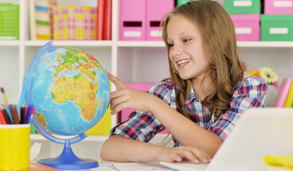 Улыбающаяся девочка школьница с глобусом