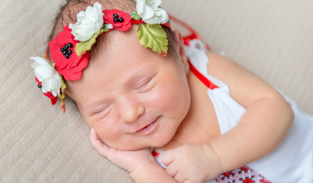 Улыбающаяся спящая девочка с венком на голове