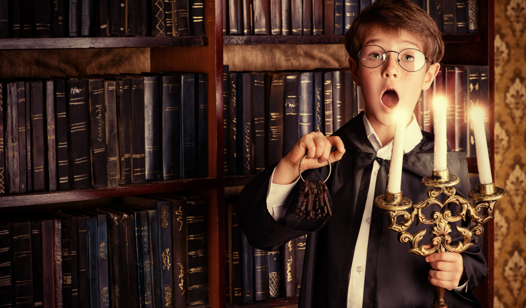 Удивленный мальчик с подсвечником со свечами в библиотеке