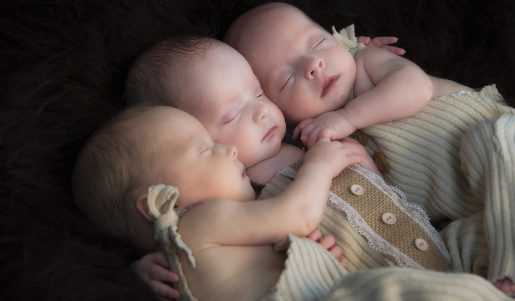 Три маленьких грудных ребенка спят обнявшись 
