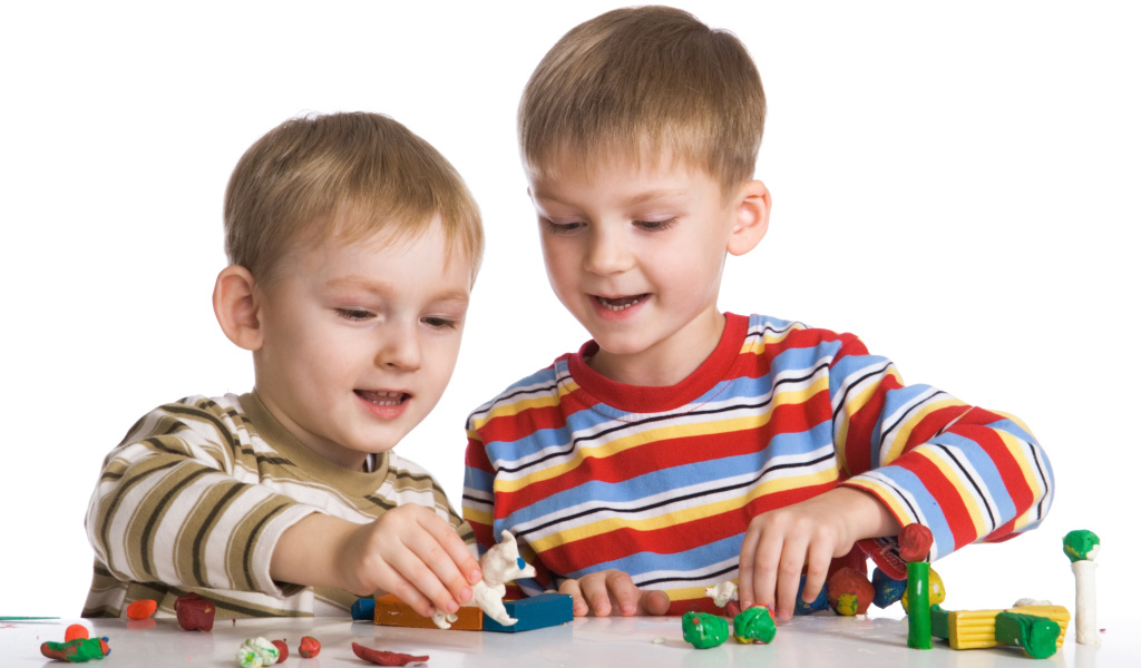 Два мальчика играют в игрушки на белом фоне