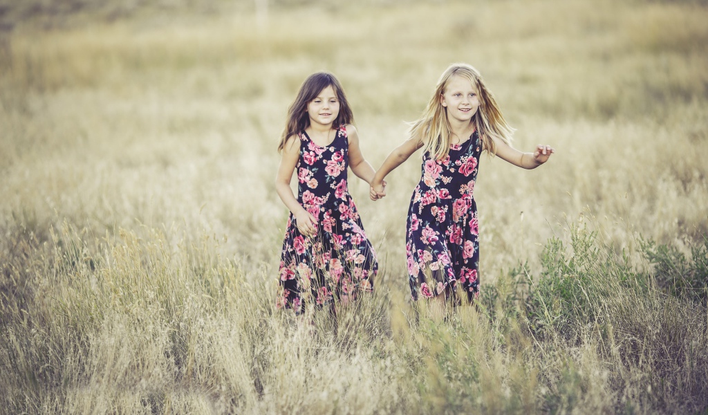 Две маленькие девочки бегут по траве