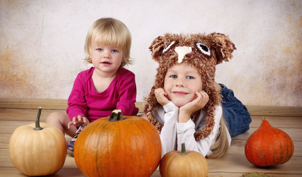 Два маленьких ребенка с тыквами в комнате