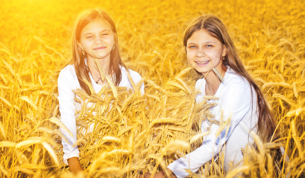 Две улыбающиеся девочки на поле с пшеницей