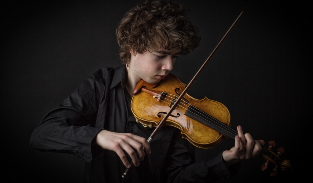 Молодой парень со скрипкой на черном фоне