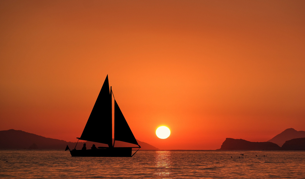 Парусная лодка в море на закате солнца