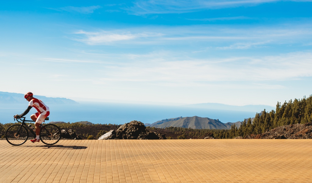 Велосипедист едет по дороге на фоне голубого неба