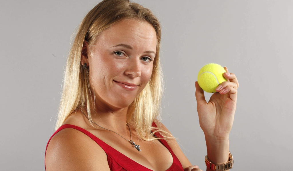 Датская теннисистка Каролина Возняцки с мячиком в руке на сером фоне