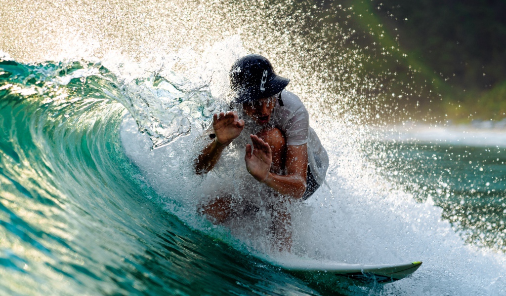 Парень серфингист ловит голубую морскую волну