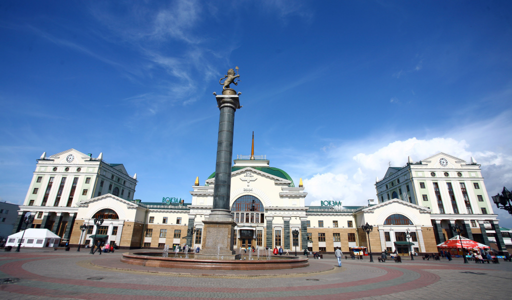 Памятник у здания железнодорожного вокзала под красивым голубым небом, Красноярск. Россия