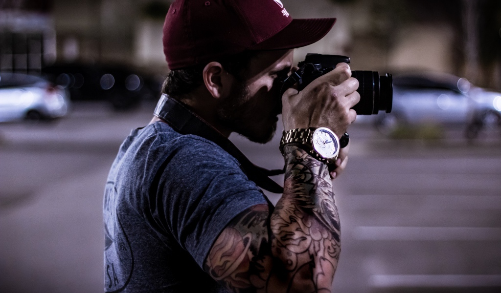 Мужчина с татуировкой на руке делает фото 