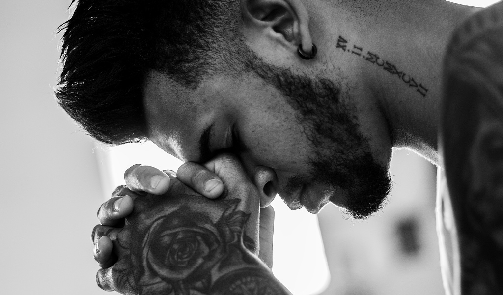 A man with tattoos on his arm and neck