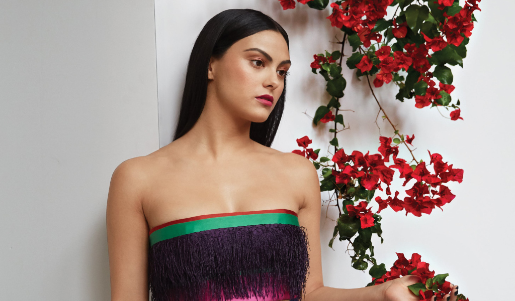 Актриса Камила Мендес стоит у стены с цветами
