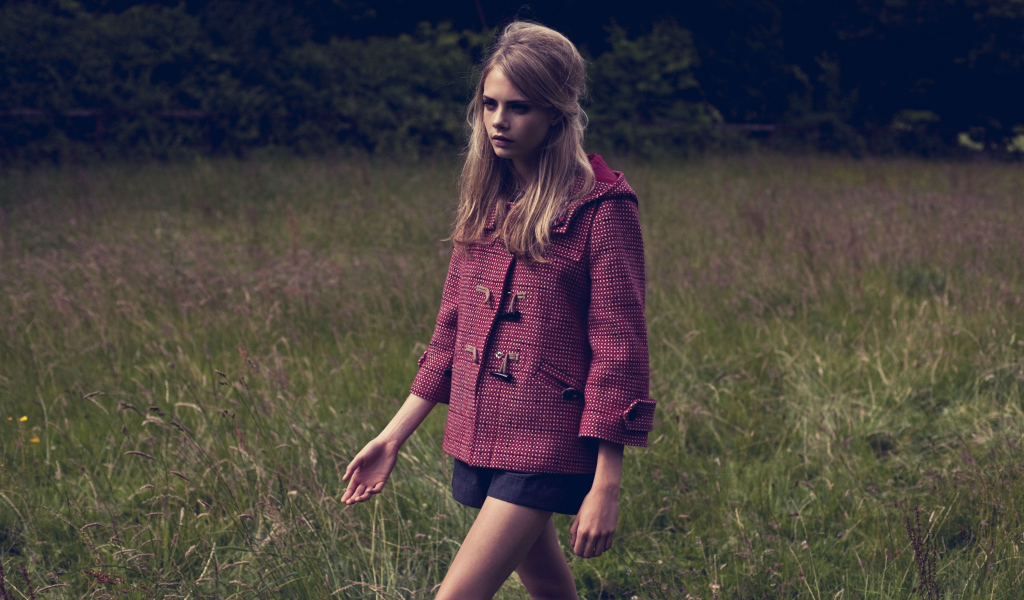 Актриса Кара Делевинь идет по траве в пальто 