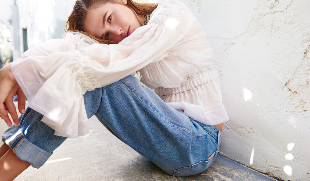 Актриса Зои Дойч сидит у стены