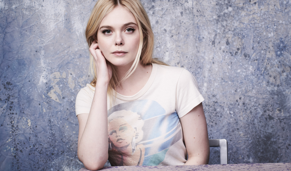 Красивая актриса Эль Фаннинг сидит за столом