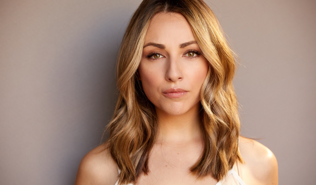 Красивая блондинка Никки Поснер на сером фоне 