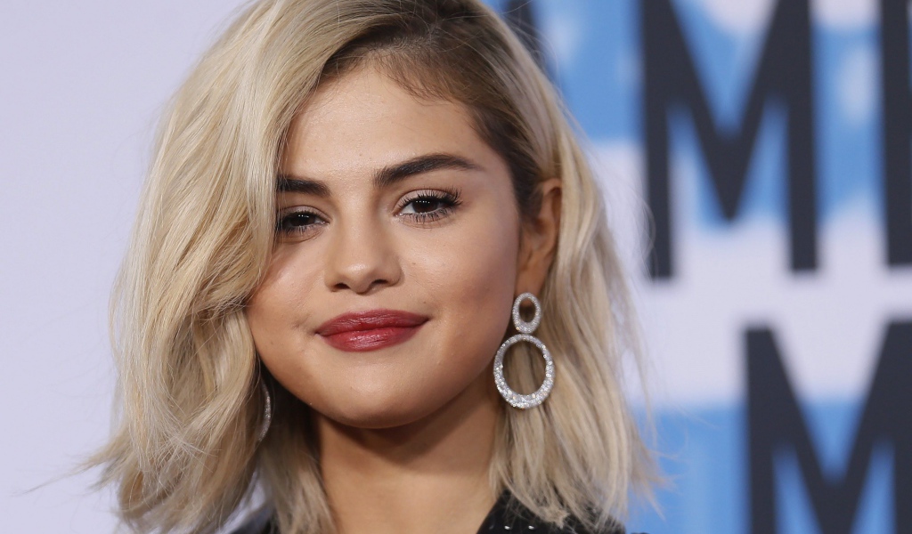 Красивая блондинка, актриса Селена Гомес с серьгами в ушах