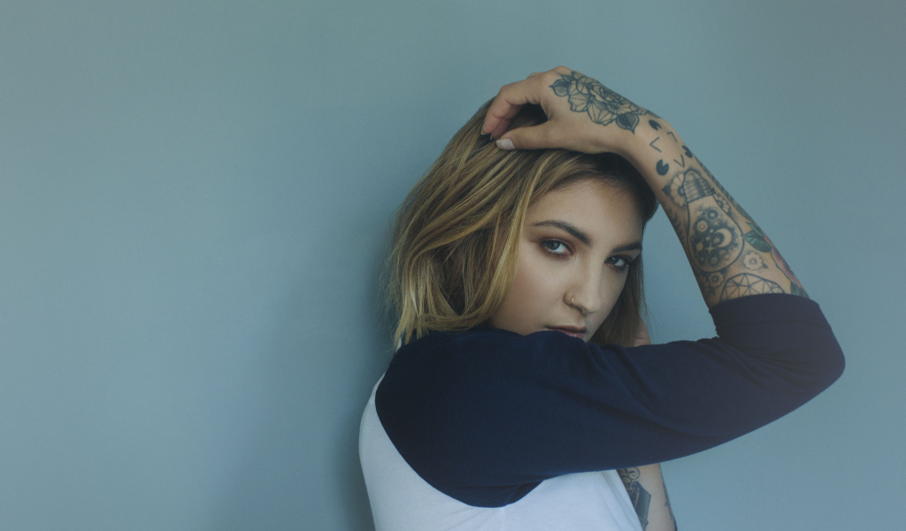 Красивая девушка стоит с татуировками на руке 