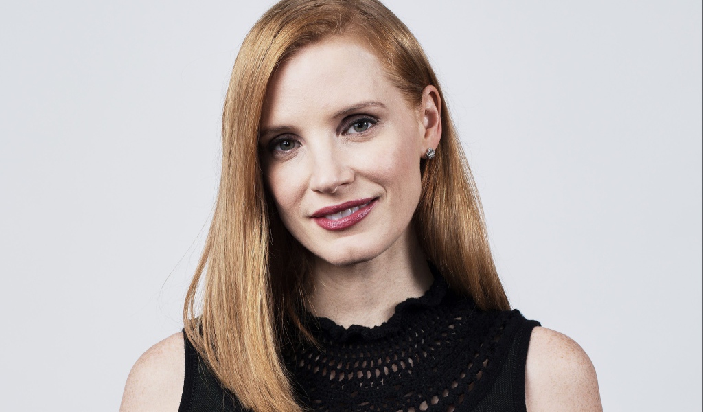 Красивая рыжеволосая актриса Джессика Честейн на сером фоне