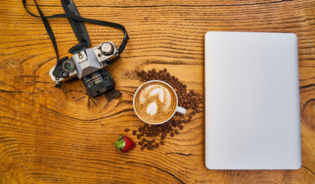 Cup of coffee on a table with a camera and laptop